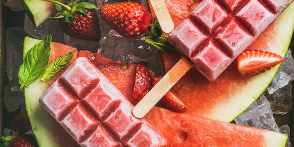 Homemade watermelon strawberry popsicles on ice with fresh fruits